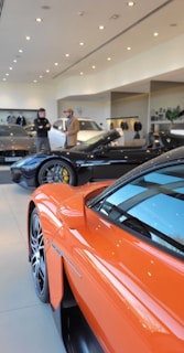 an orange sports car is parked in a showroom