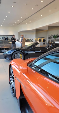 an orange sports car is parked in a showroom