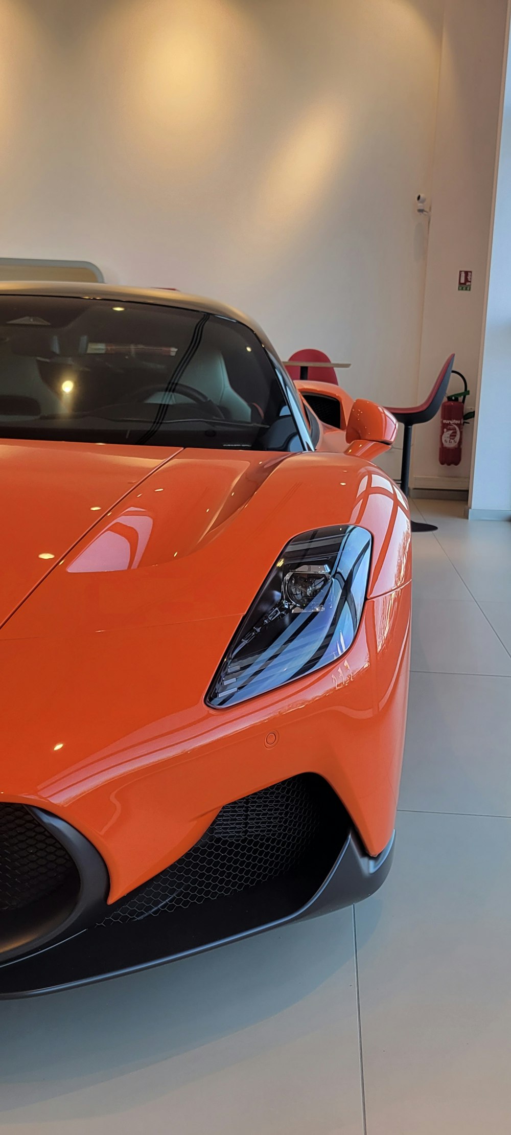 an orange sports car parked in a showroom