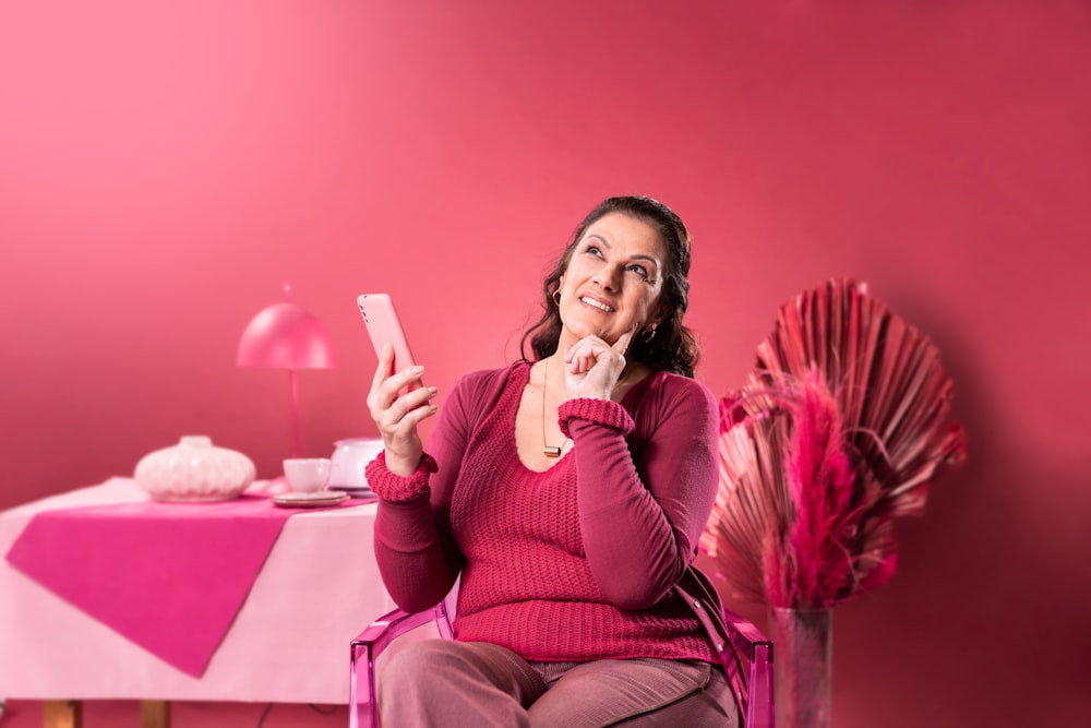 a woman sitting in a chair holding a cell phone