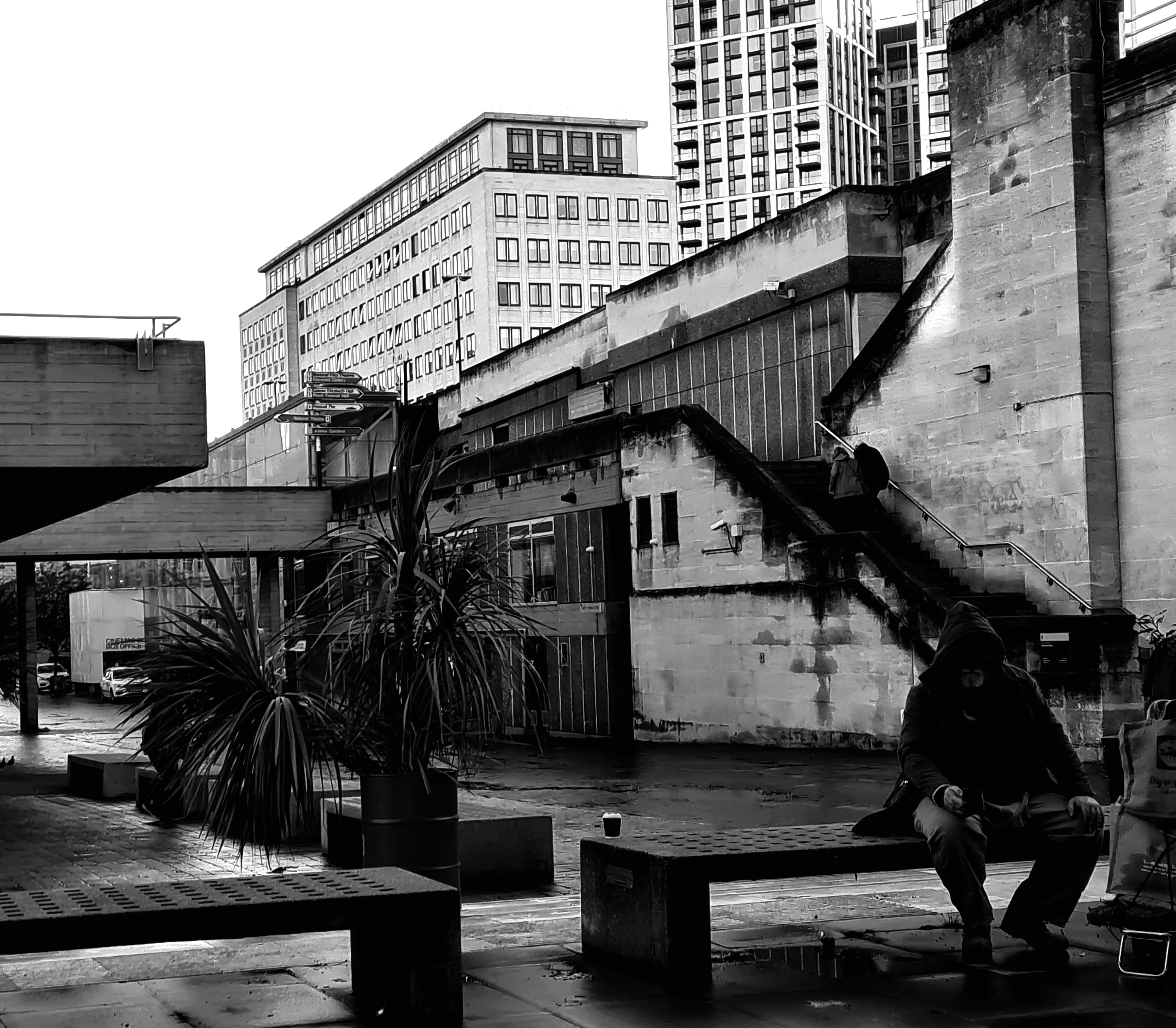 a black and white photo of a person sitting on a bench