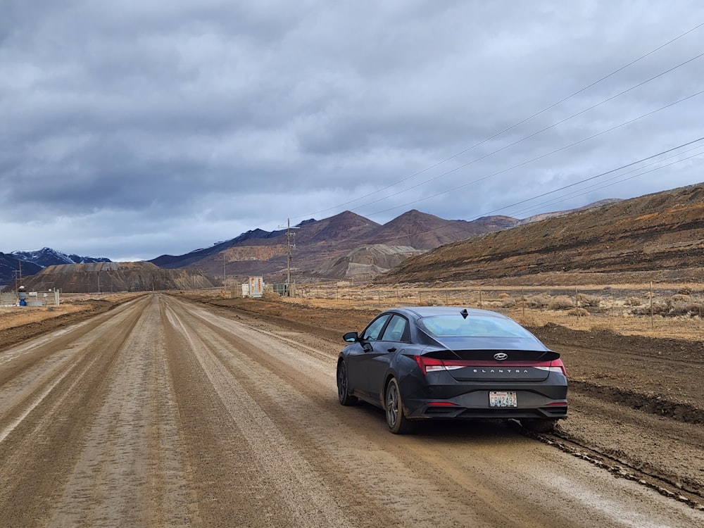 a car parked on a dirt road in the middle of nowhere