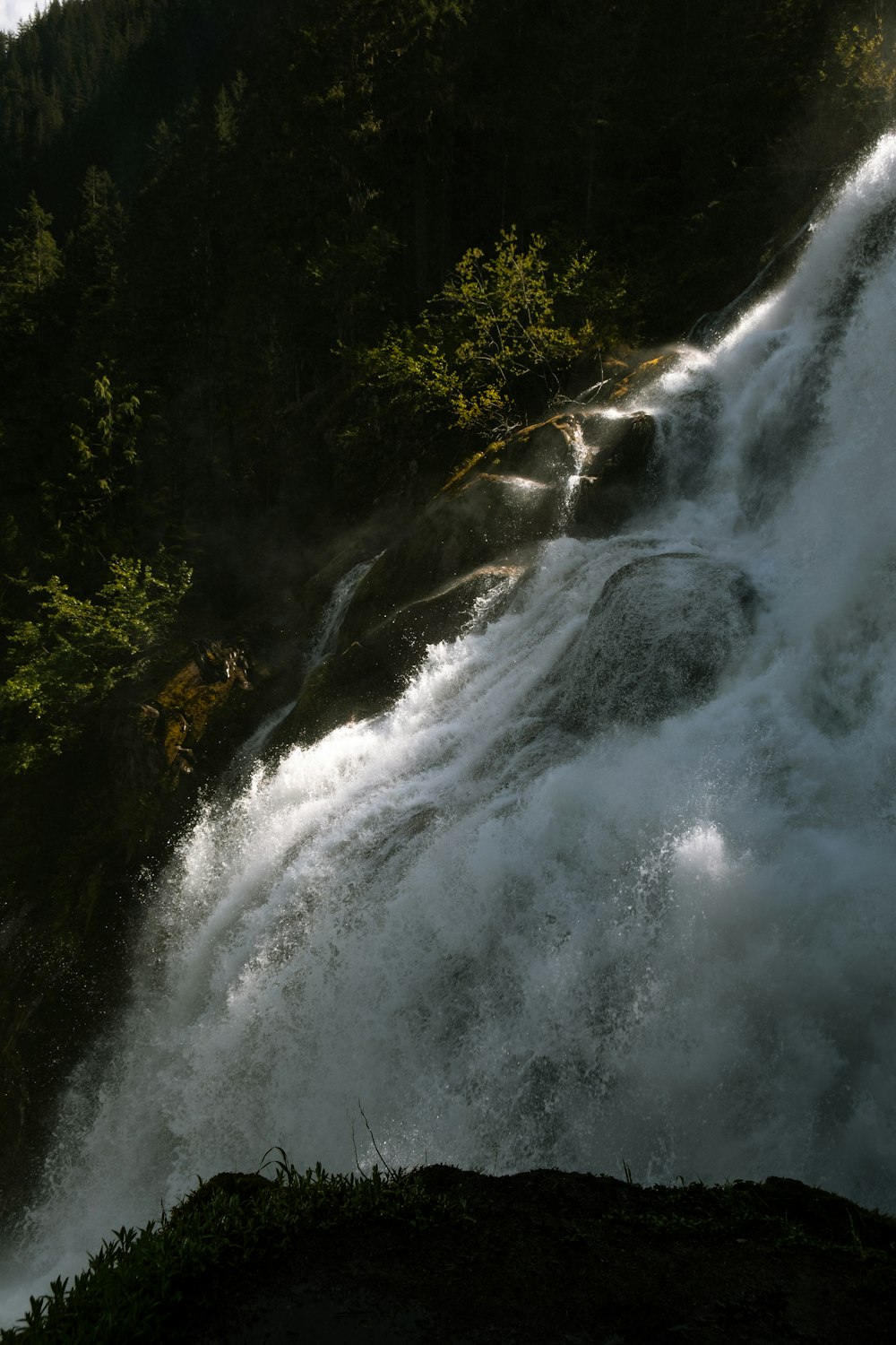 a man standing on a cliff next to a waterfall