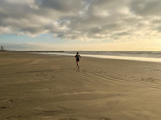 A person running on a beach near the ocean