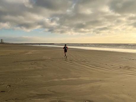 A person running on a beach near the ocean