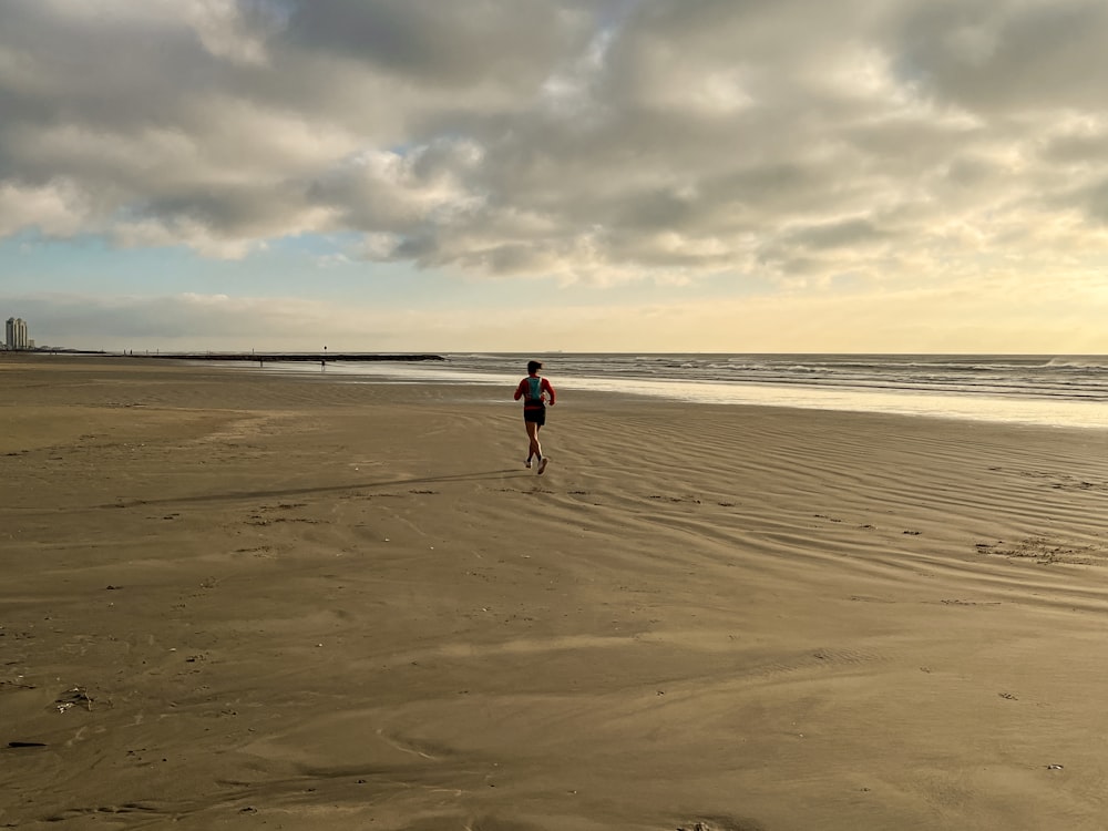 a person running on a beach near the ocean