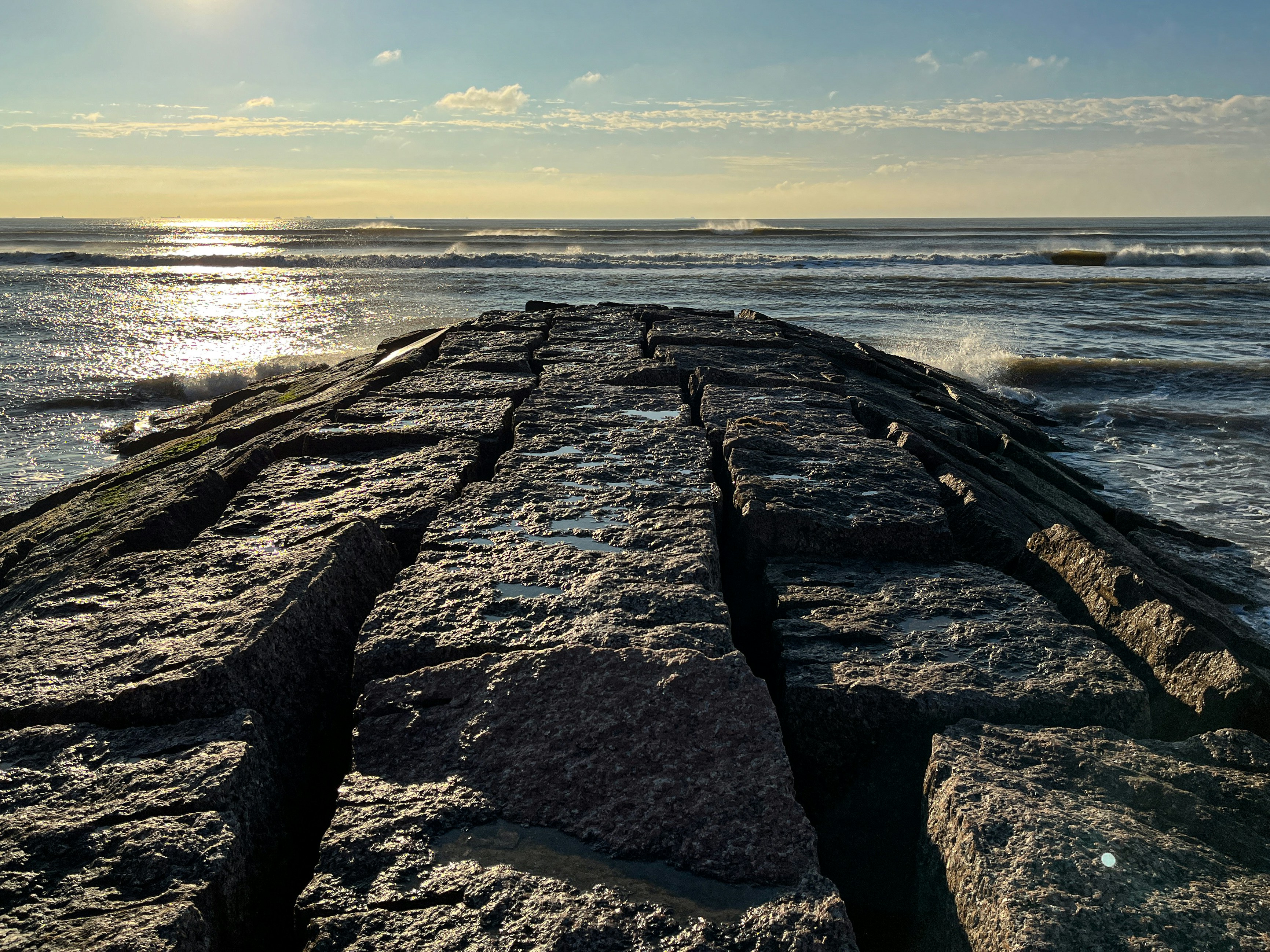 the sun is shining over the water and rocks