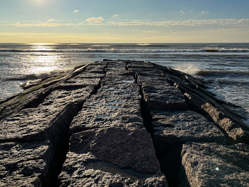 the sun is shining over the water and rocks