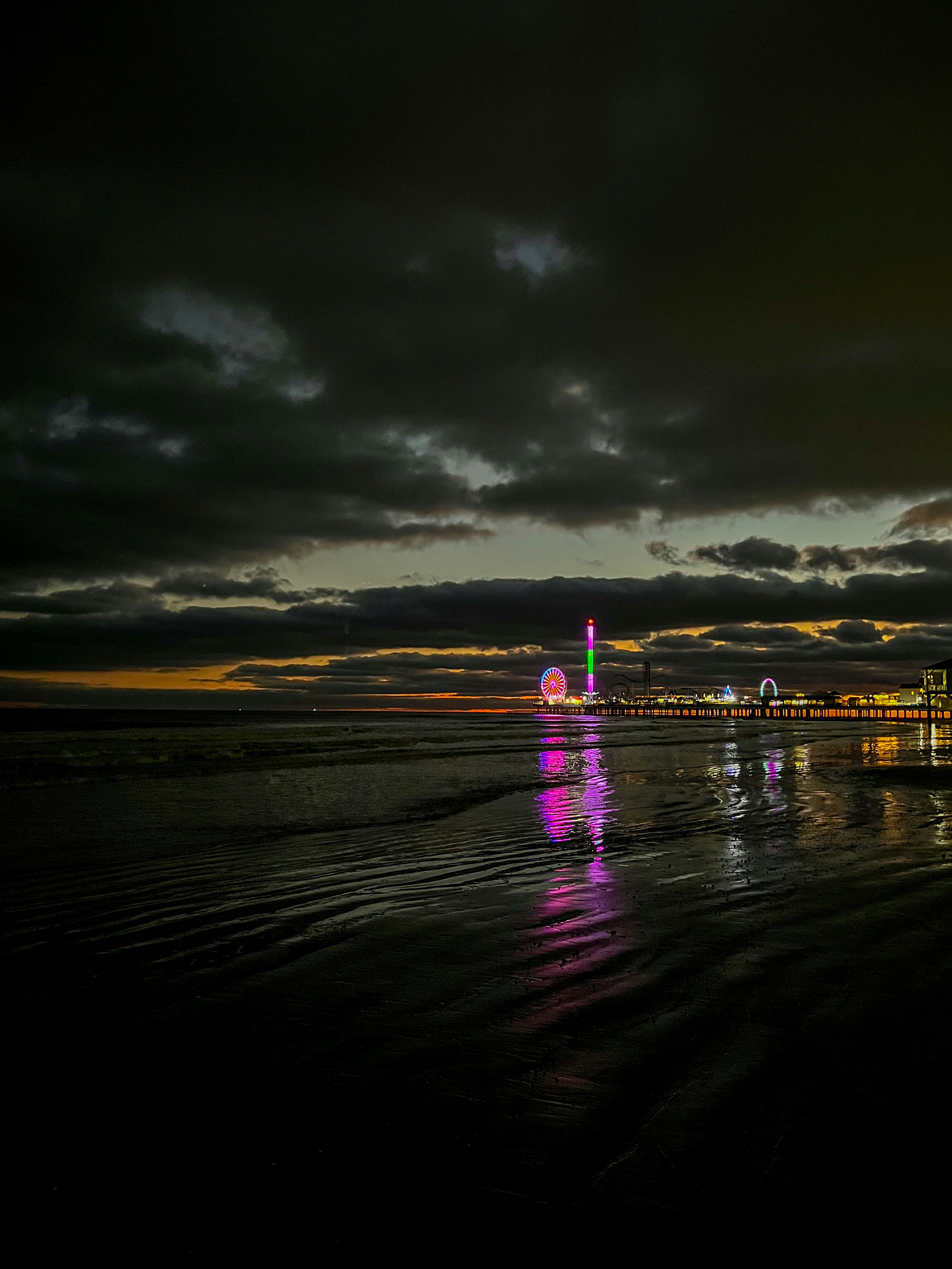 a beach with a ferris wheel in the distance