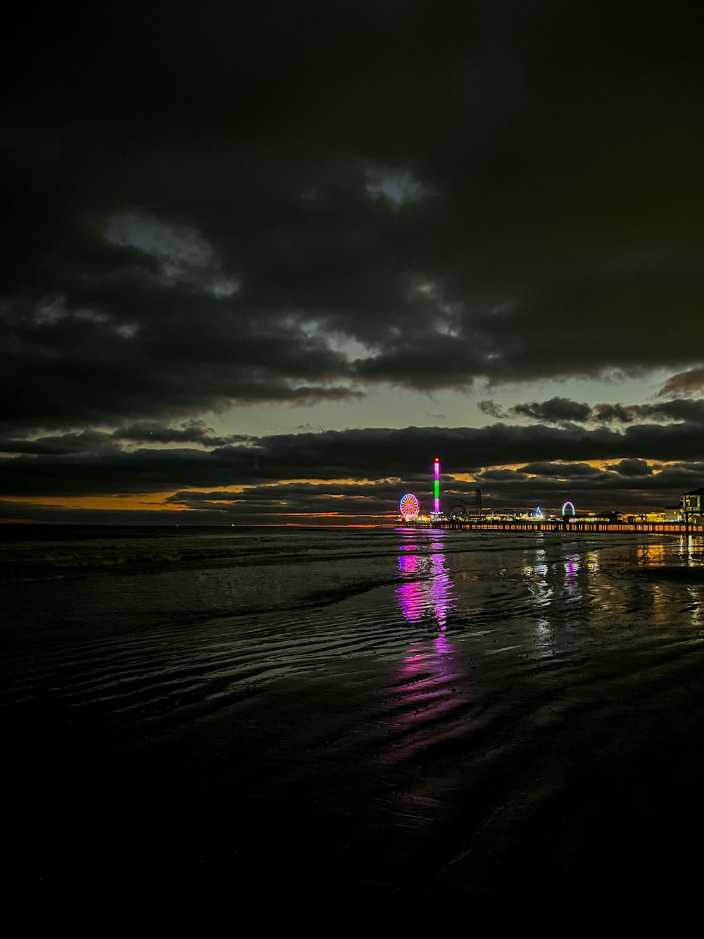 a beach with a ferris wheel in the distance