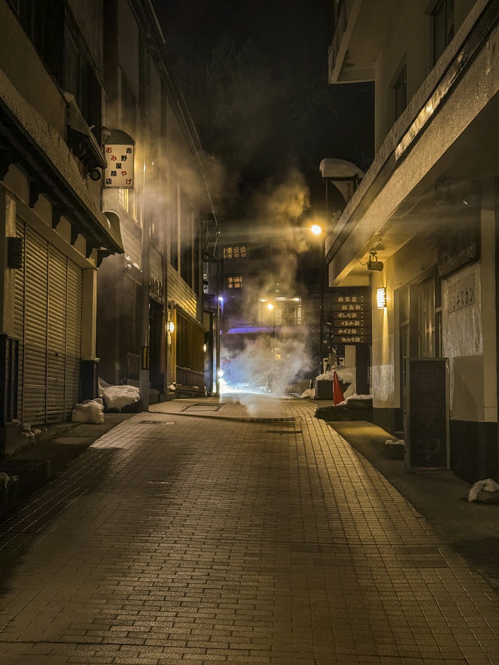 a city street at night with steam coming out of the buildings