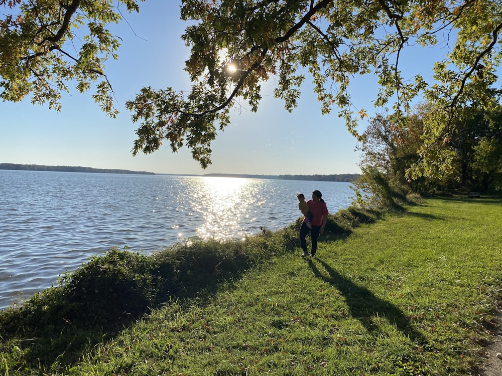 two people walking along a path next to a body of water