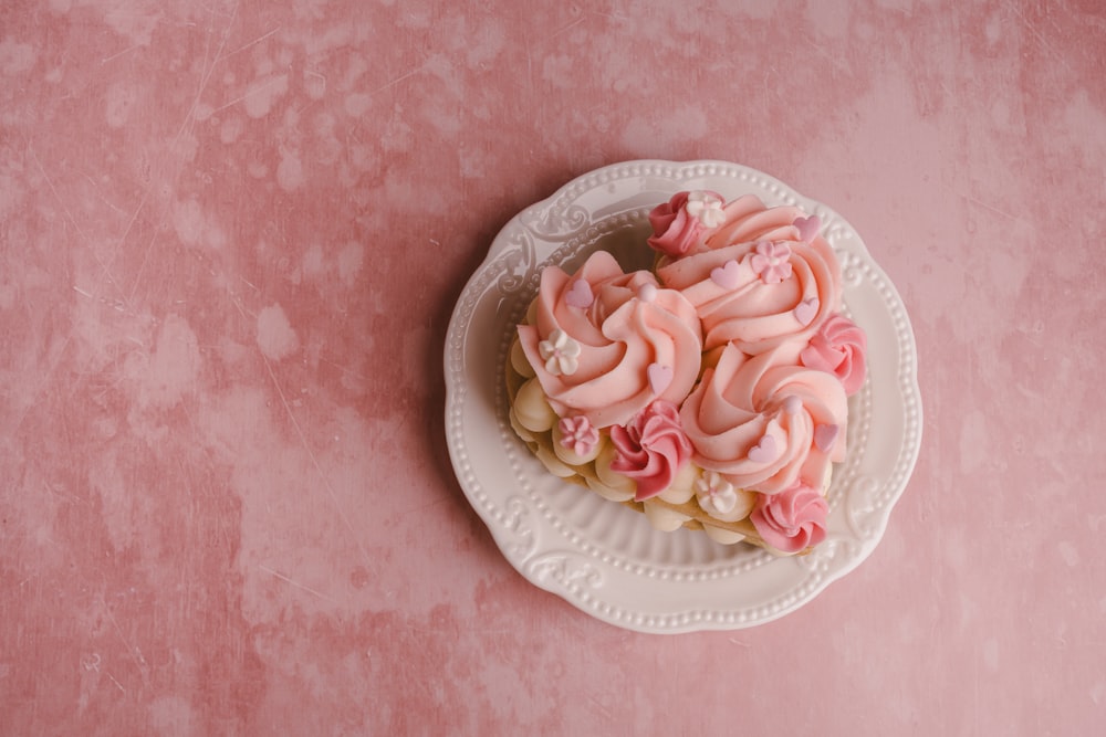 a white plate topped with pink frosting on top of a pink table