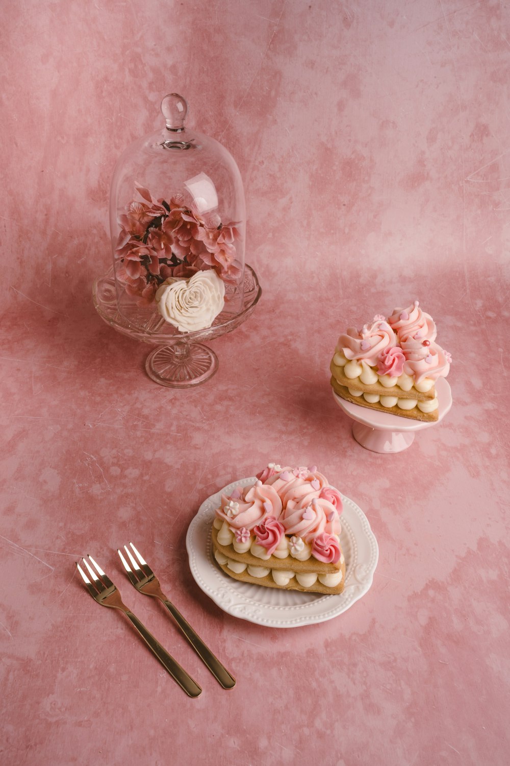 a pink table topped with two cakes covered in frosting