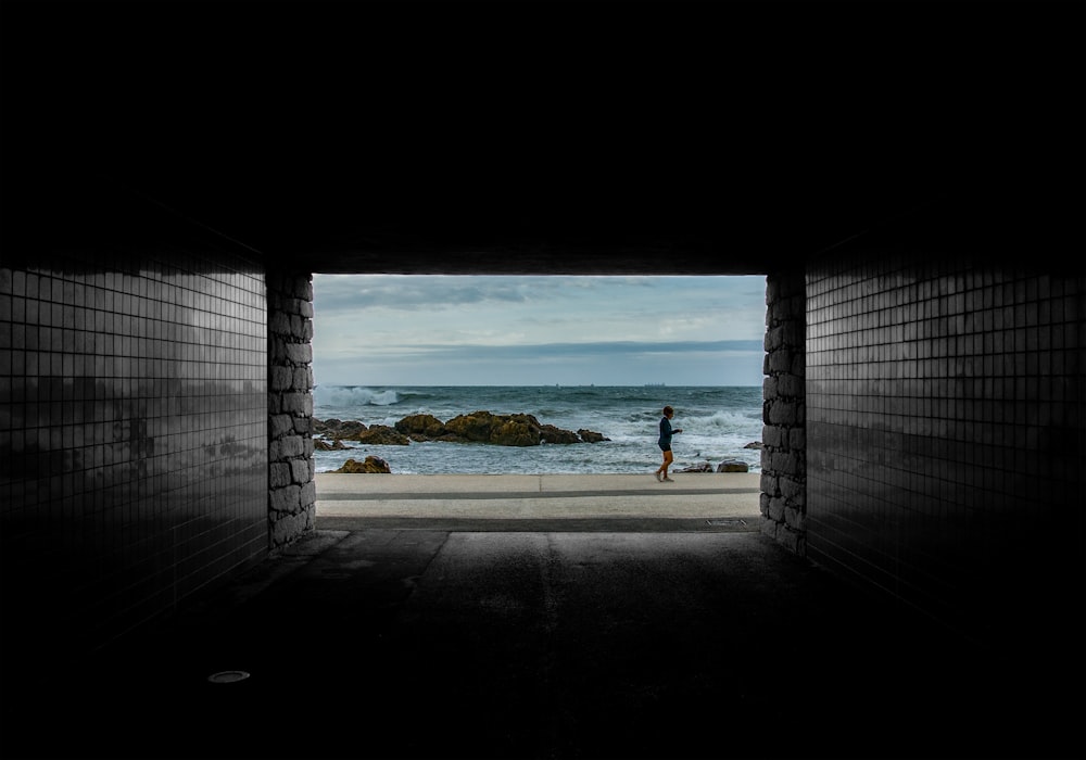 a person walking out of a tunnel into the ocean