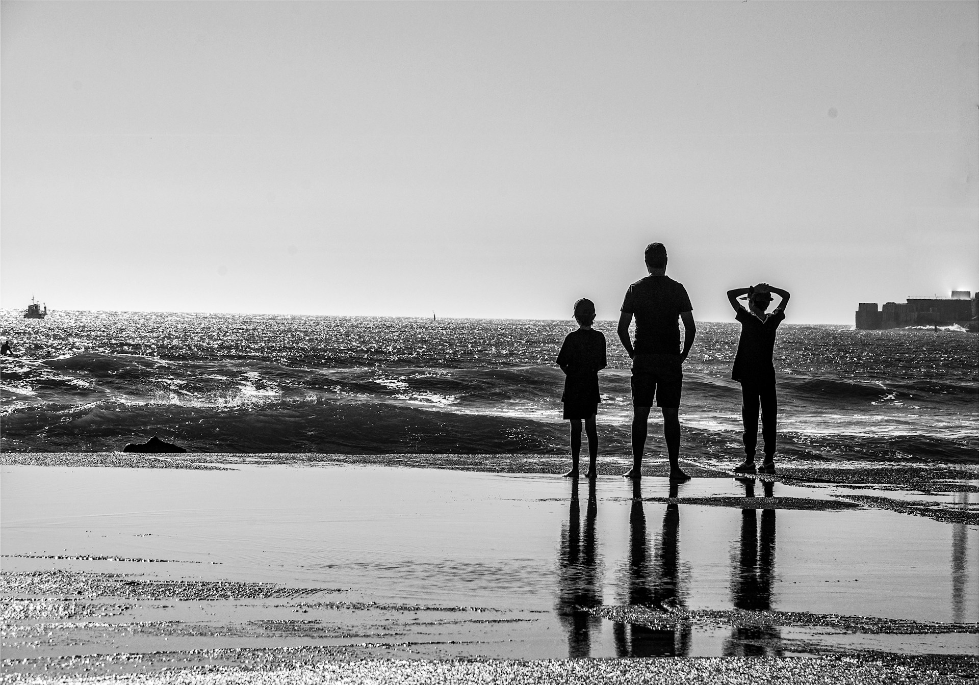 a black and white photo of a family on the beach