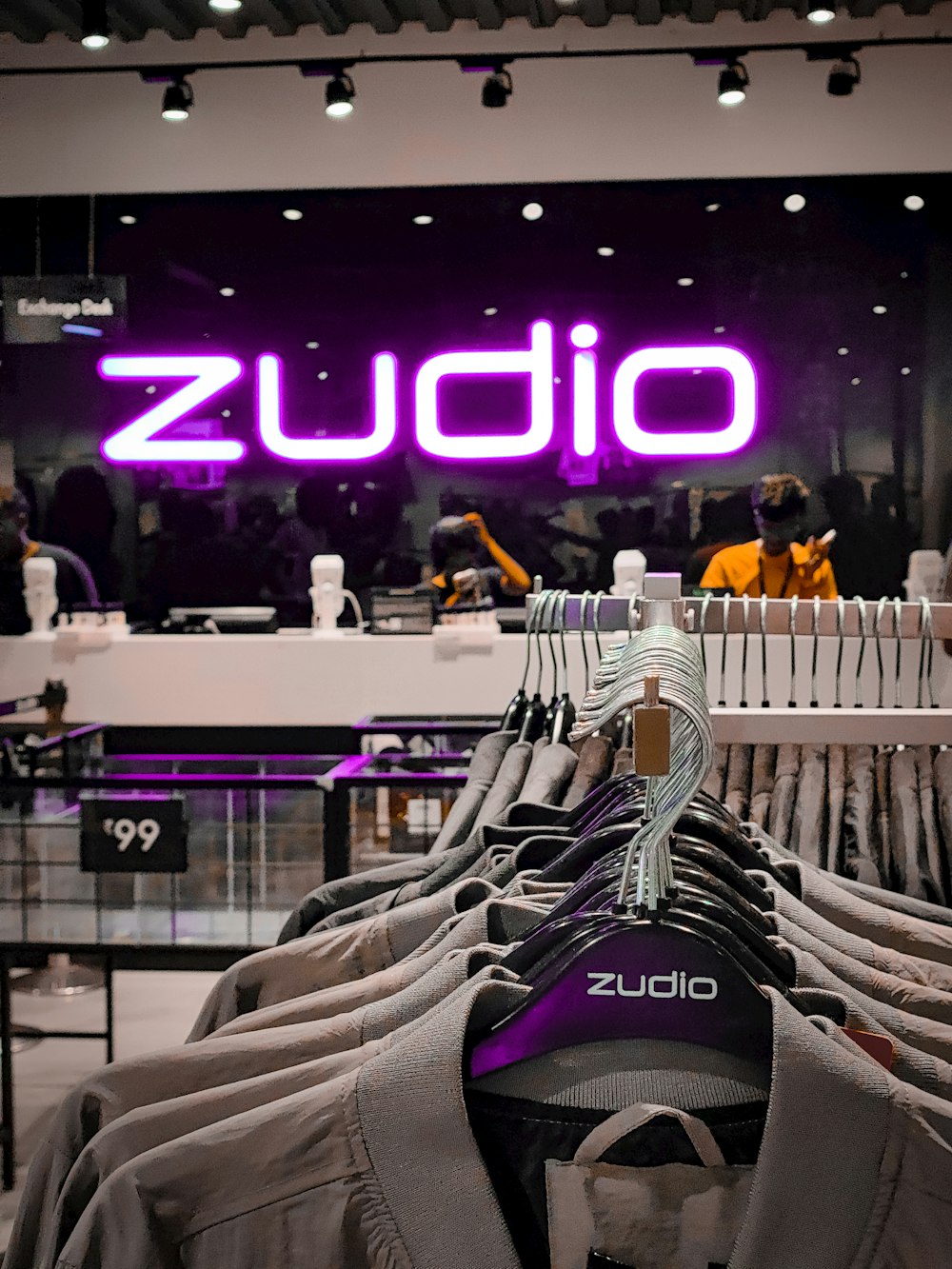 a purple sign that reads zudio hanging on a rack