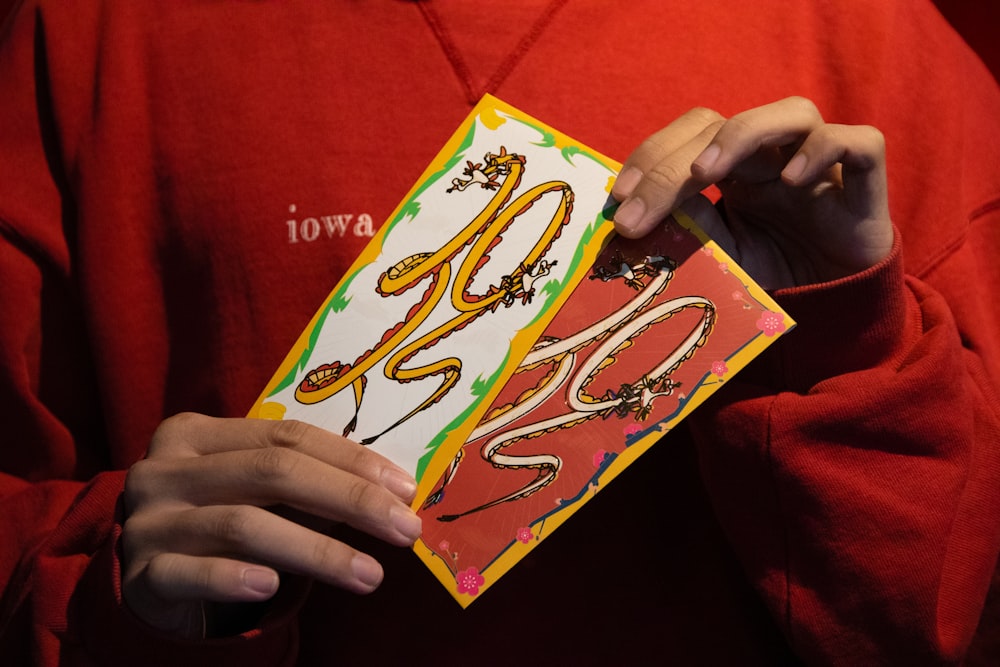 a person in a red shirt holding a card with a snake on it