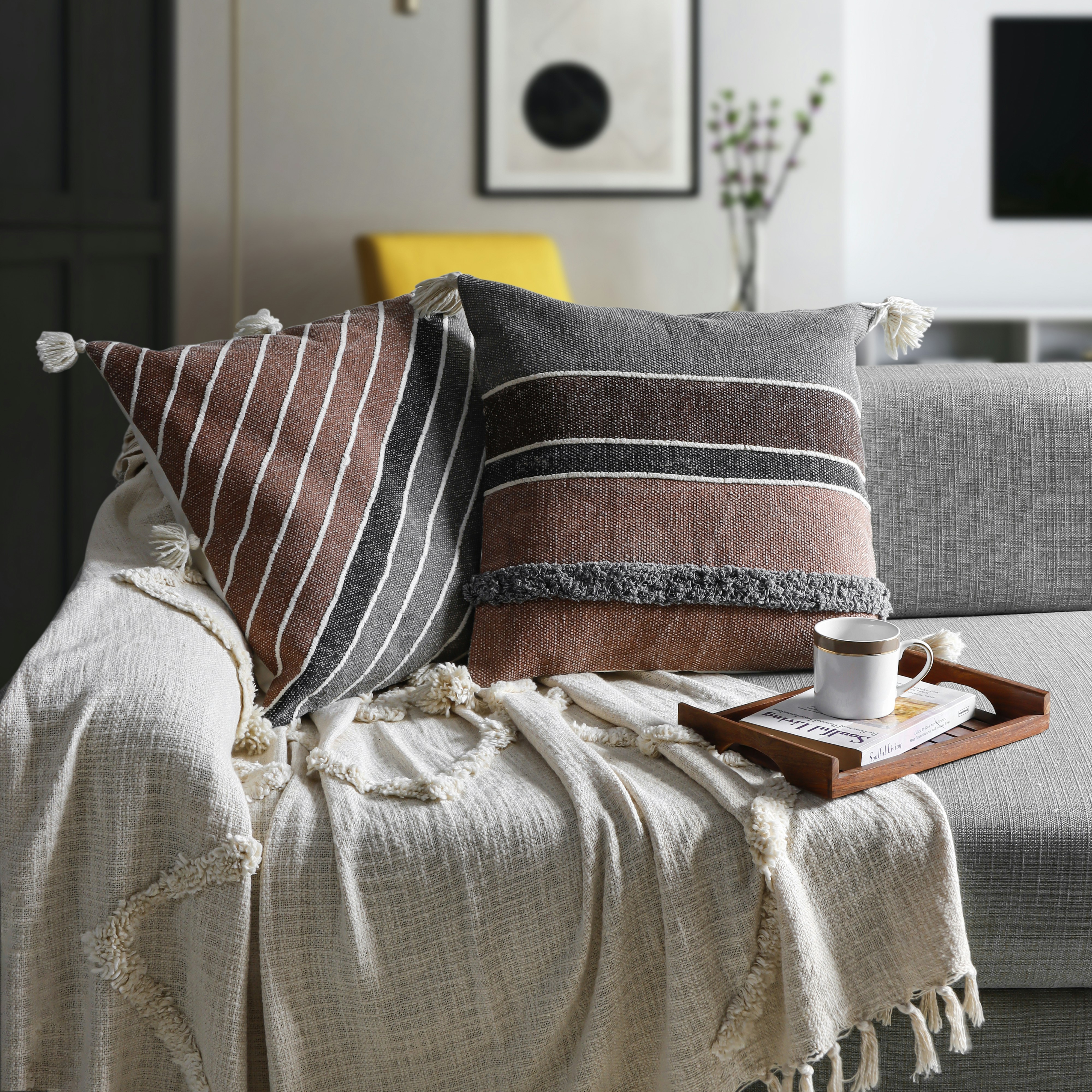 a coffee cup on a tray on a couch with pillow and throws