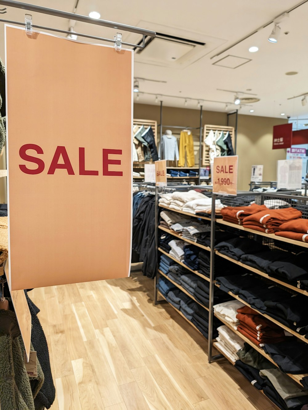 a clothing store with a sale sign hanging from the ceiling