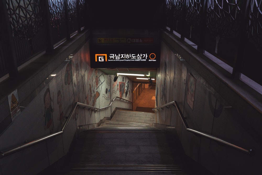 an escalator in a subway station with a sign above it