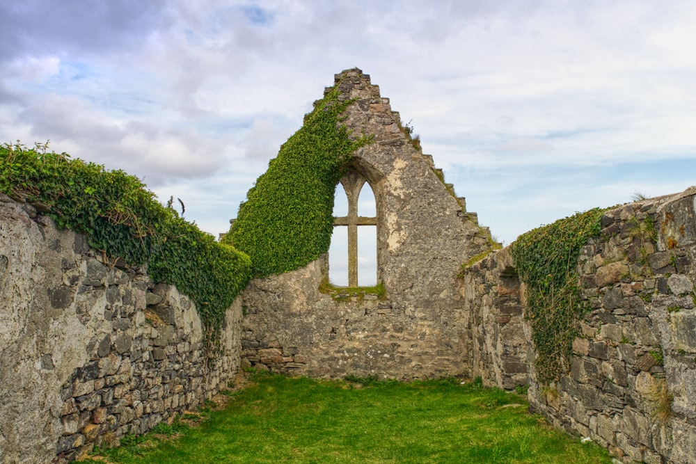 a stone wall with a window and ivy growing on it