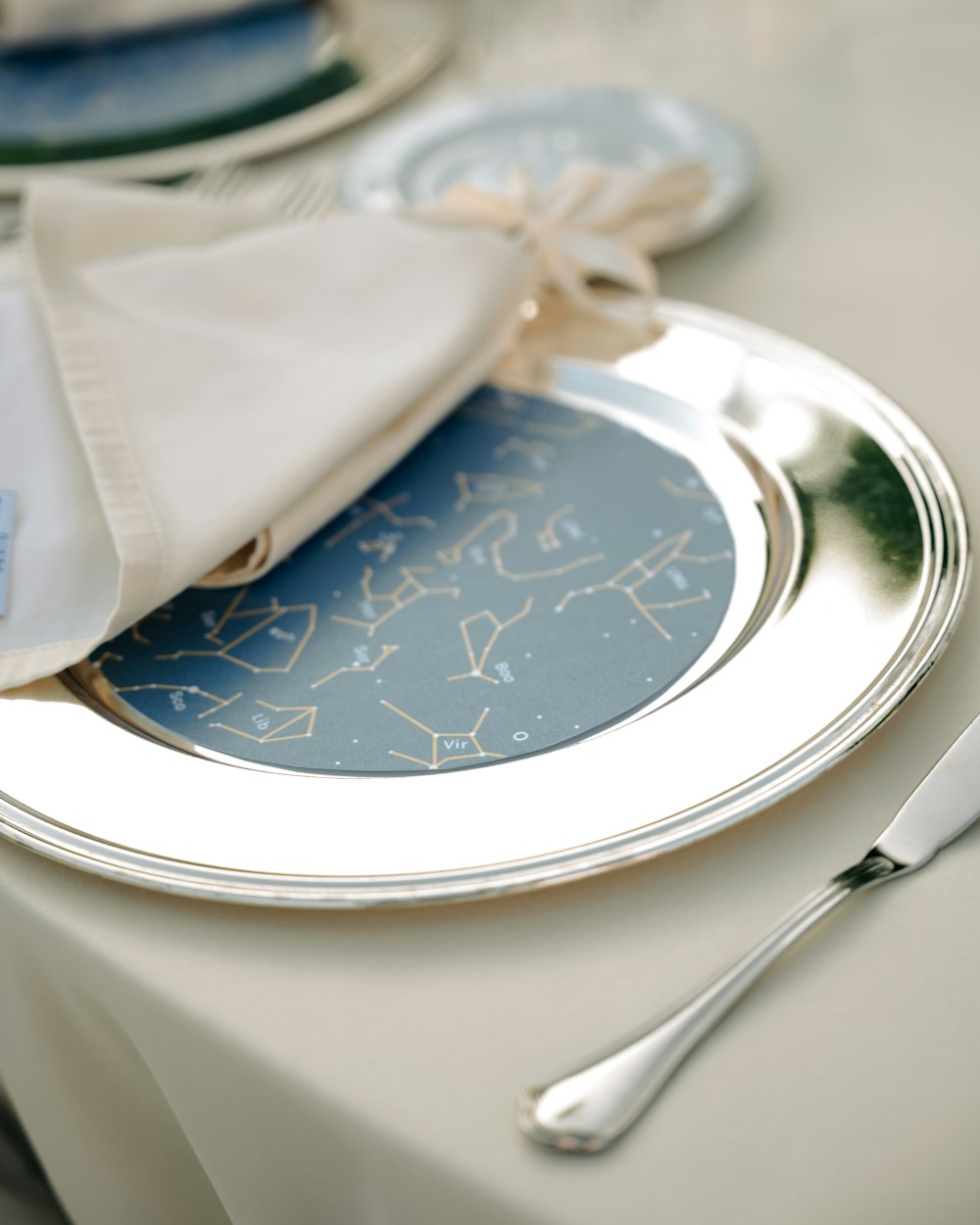 a white table with a silver plate and silverware