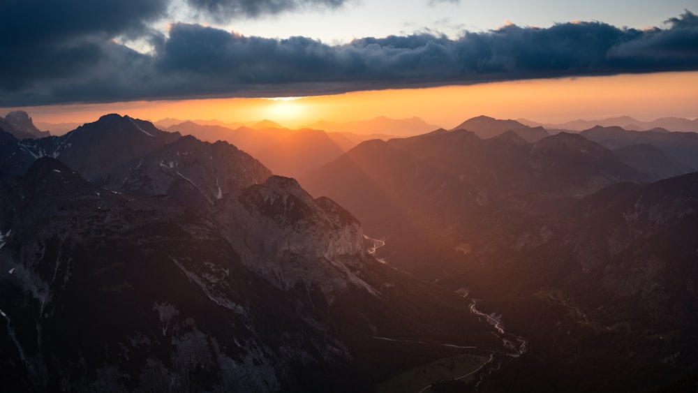 the sun is setting over a mountain range