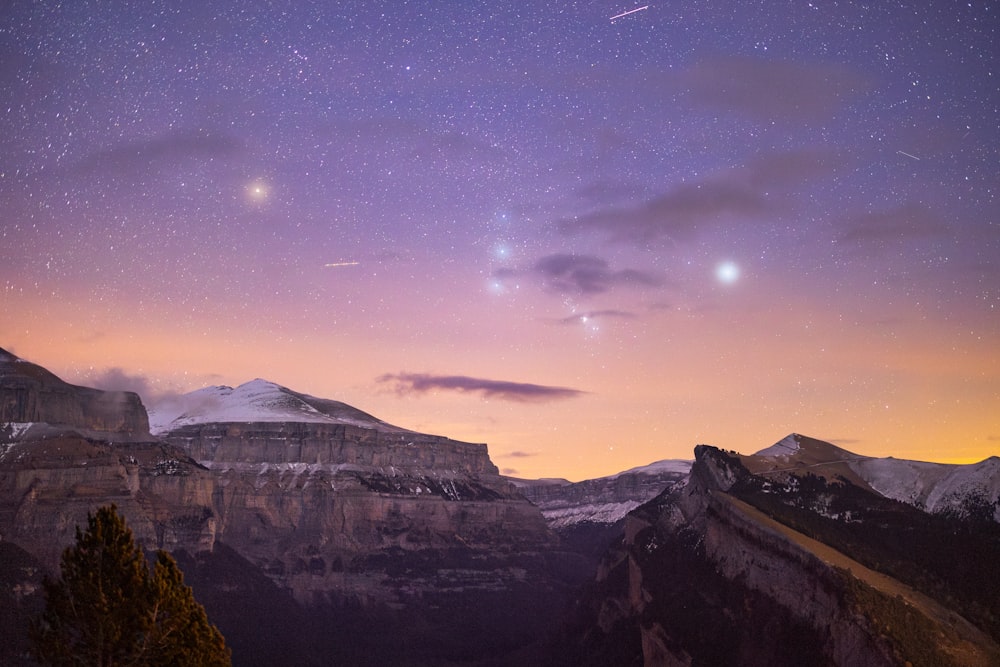 the night sky with stars above a mountain range