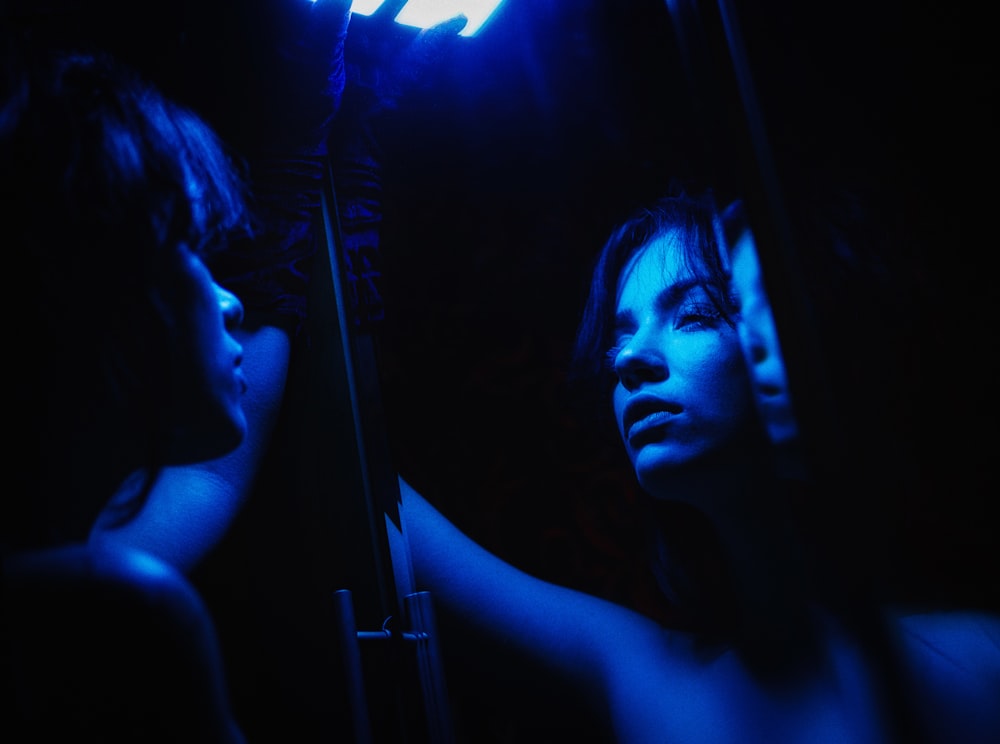 a woman standing in front of a mirror in the dark