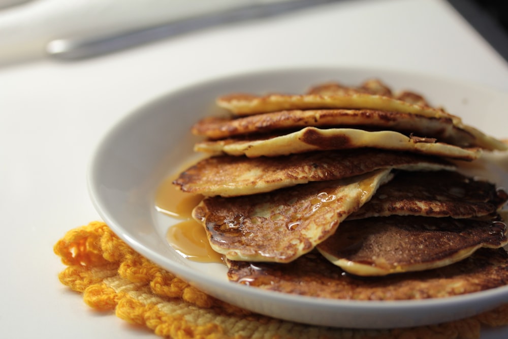 a white plate topped with pancakes covered in syrup