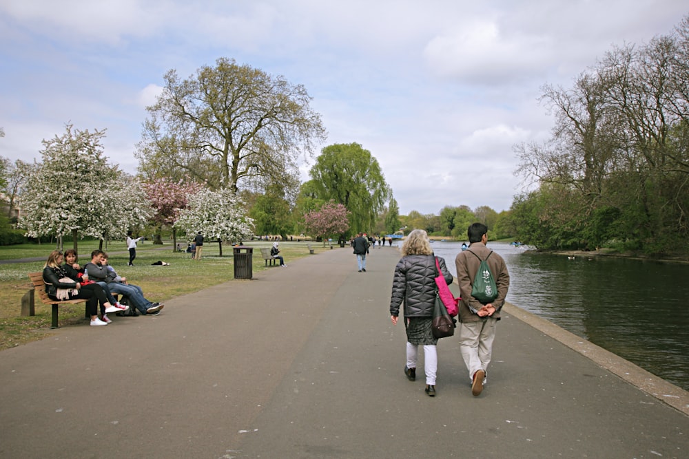 a group of people walking down a path next to a river