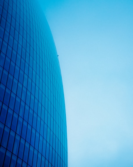 a plane flying in the sky near a building