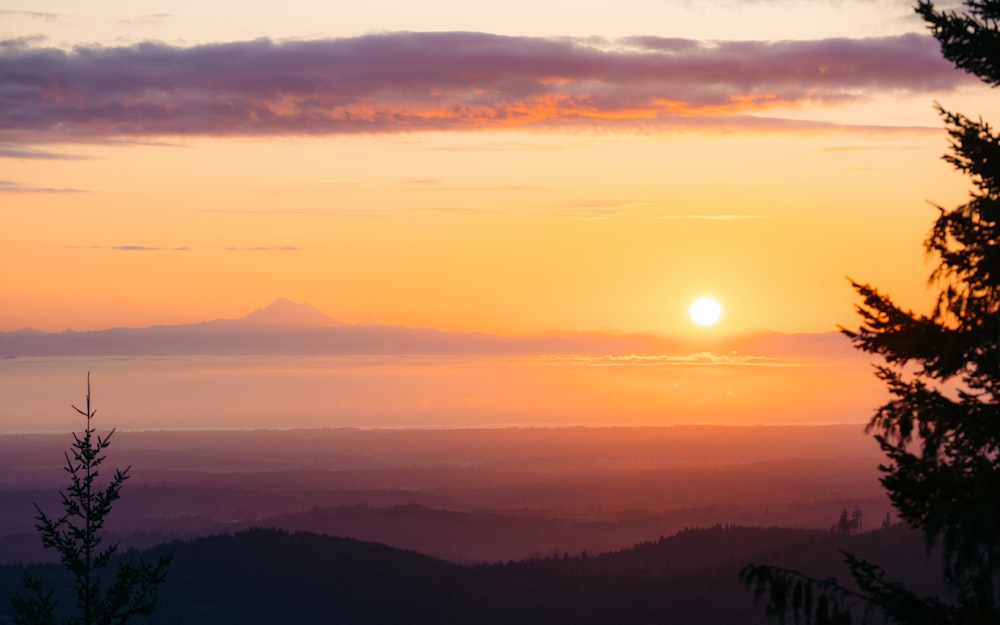 the sun is setting over a mountain range