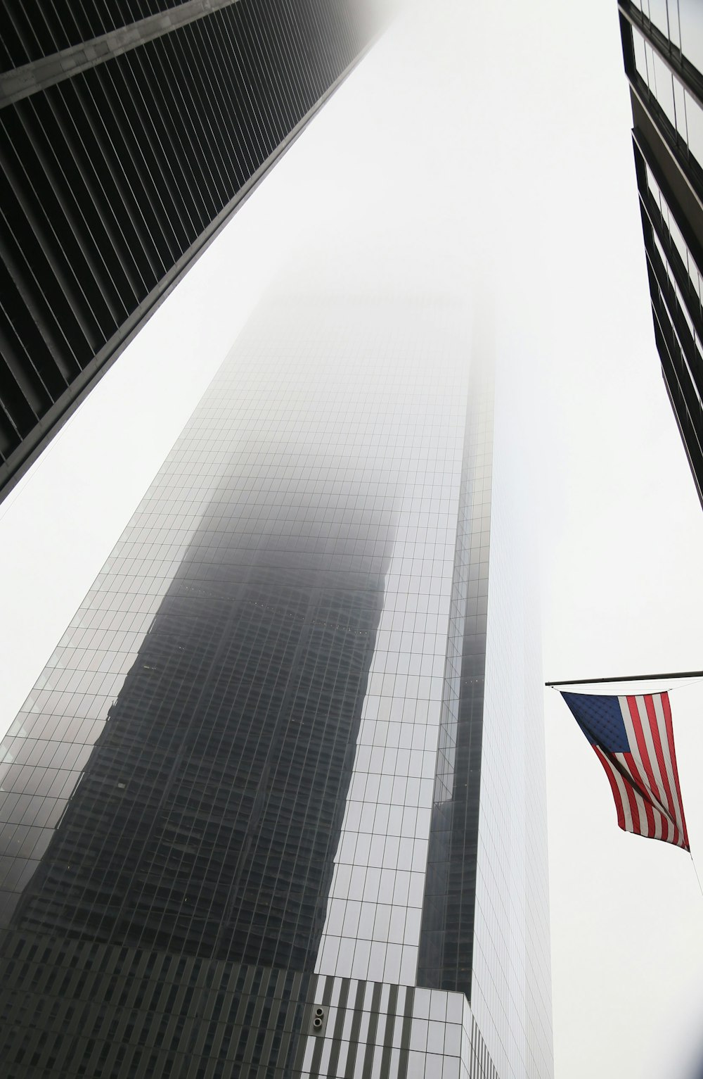 Un edificio alto con dos banderas estadounidenses ondeando frente a él