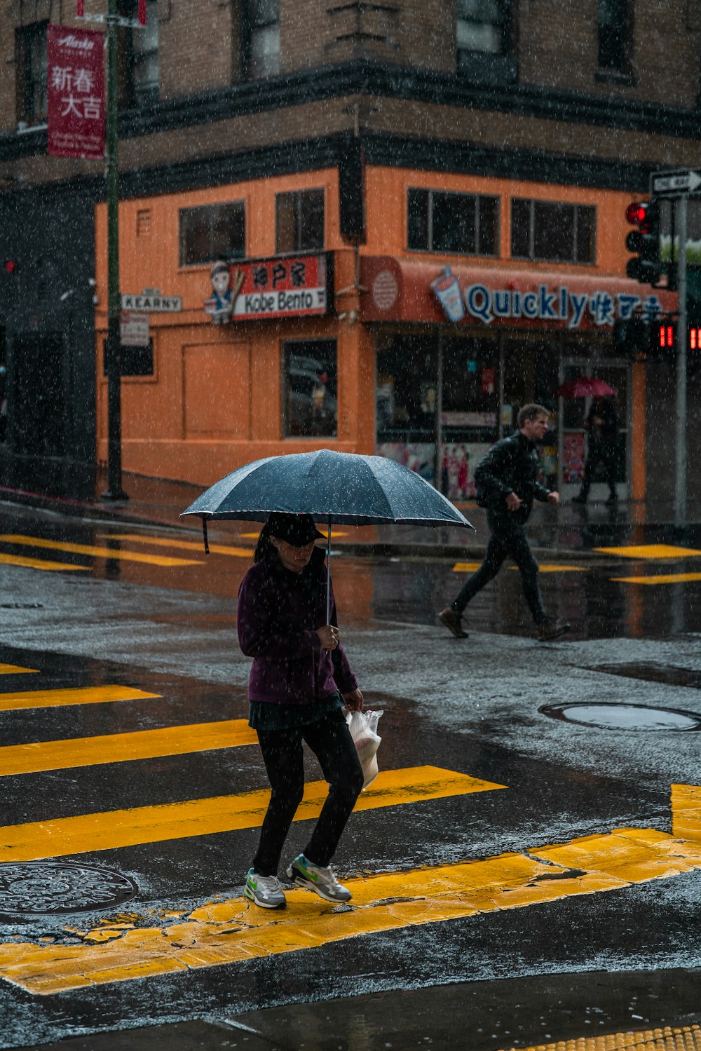 a woman walking across a street holding an umbrella