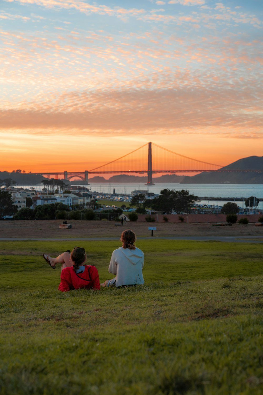 a couple of people sitting on top of a lush green field