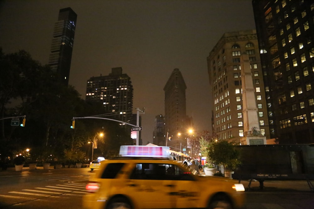 a yellow taxi cab driving down a street at night