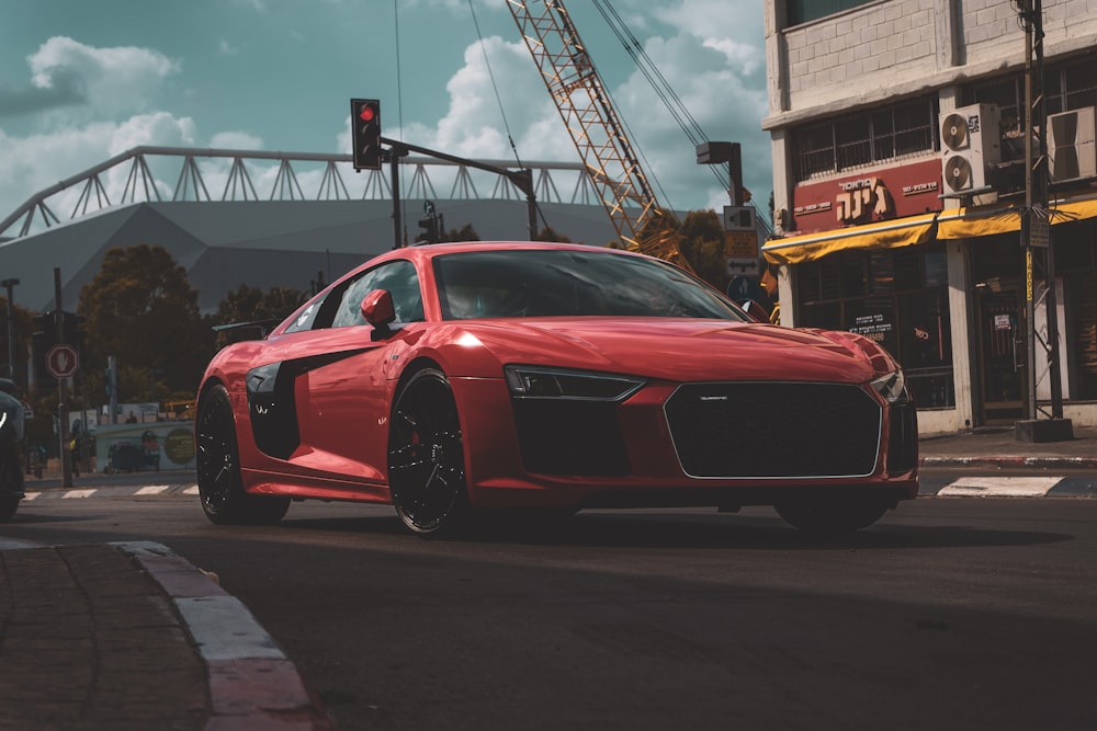 a red car driving down a street next to a traffic light