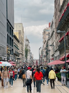 a group of people walking down a street next to tall buildings