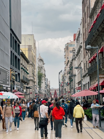 a group of people walking down a street next to tall buildings