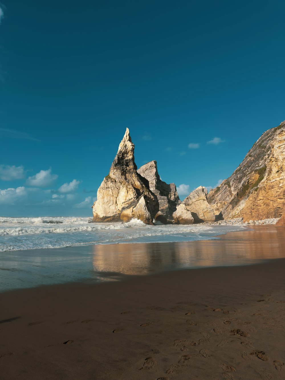 una gran roca que sobresale del océano junto a una playa