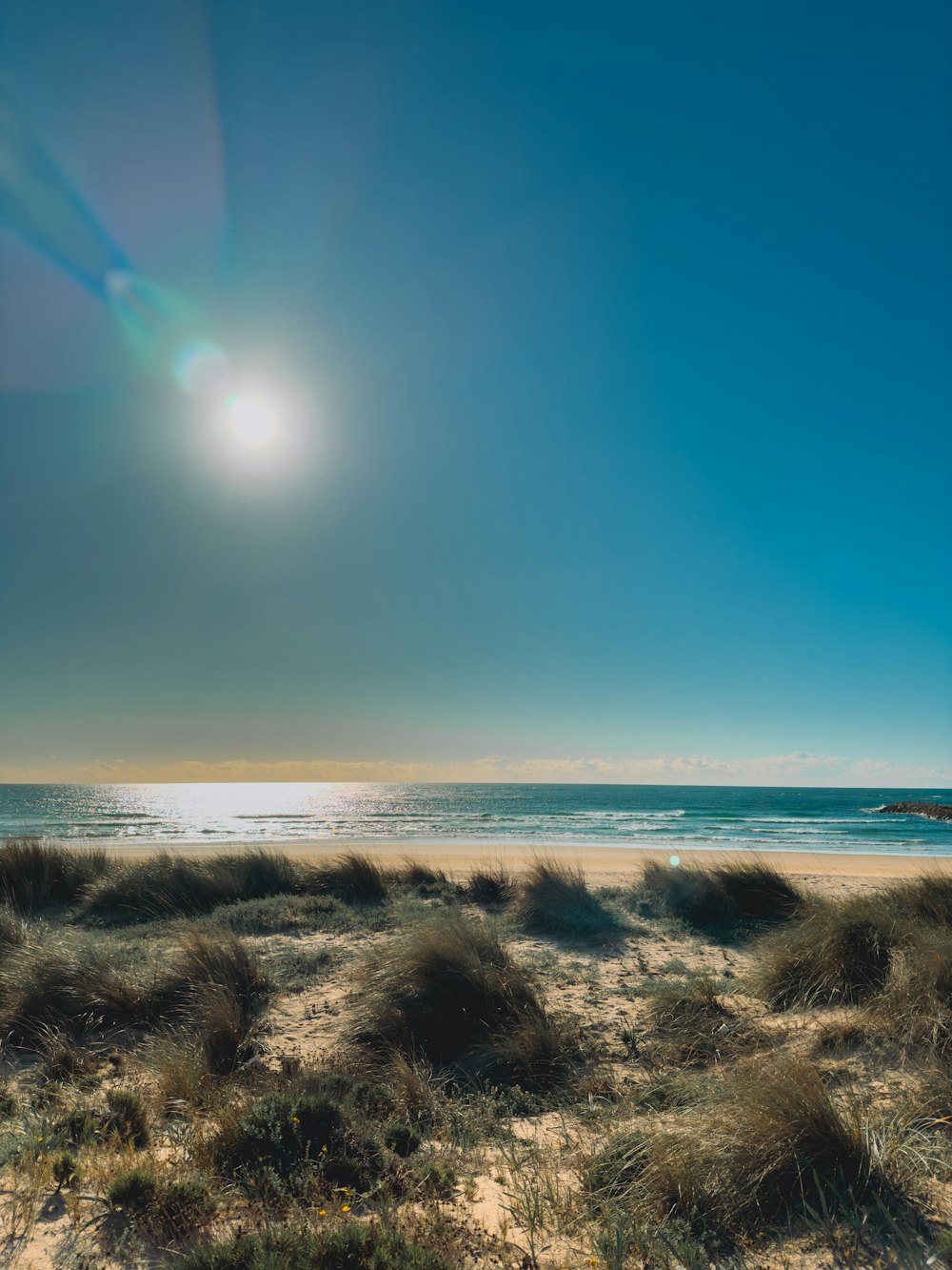 the sun is shining over the beach and the ocean