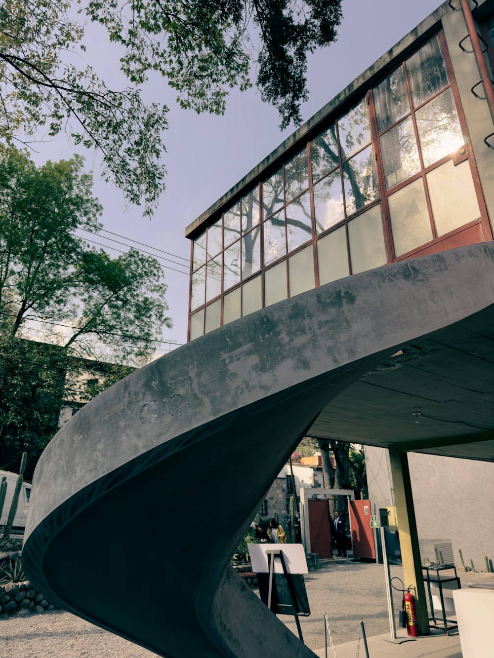 a curved concrete structure with a building in the background