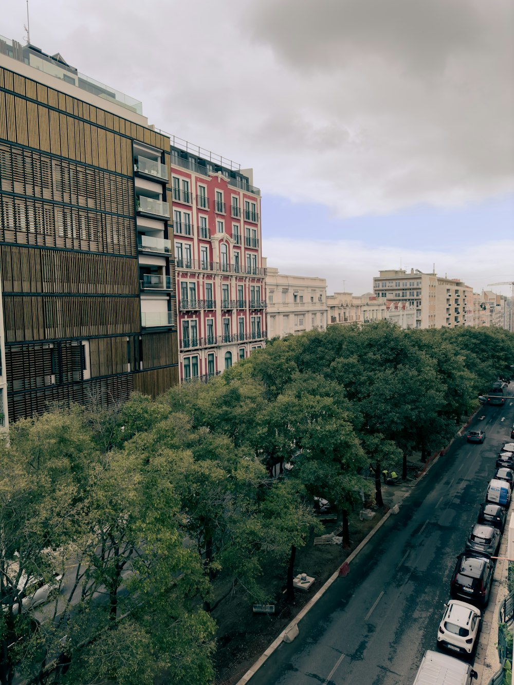 a city street lined with parked cars and tall buildings