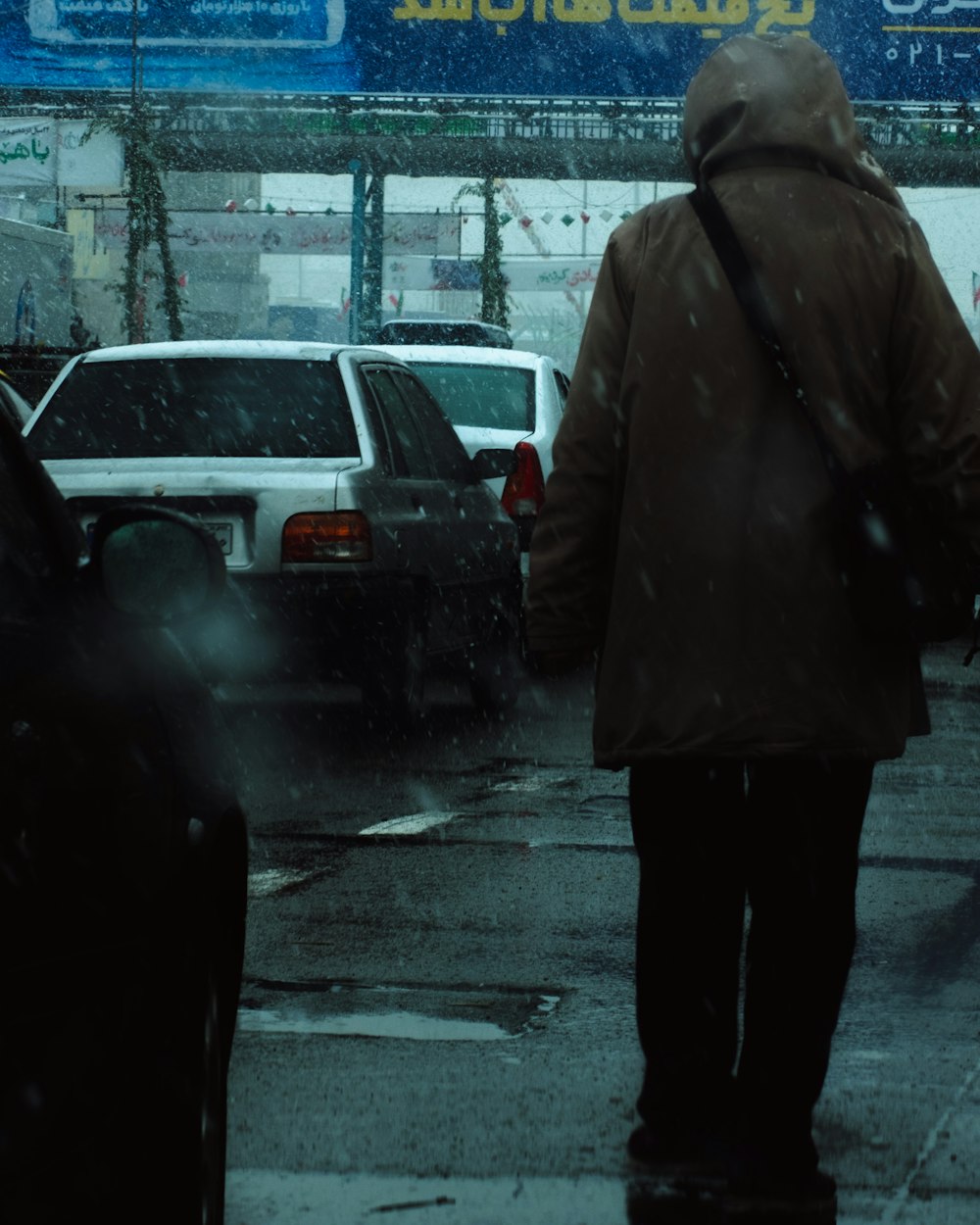 ein Mann, der im Regen die Straße entlang geht