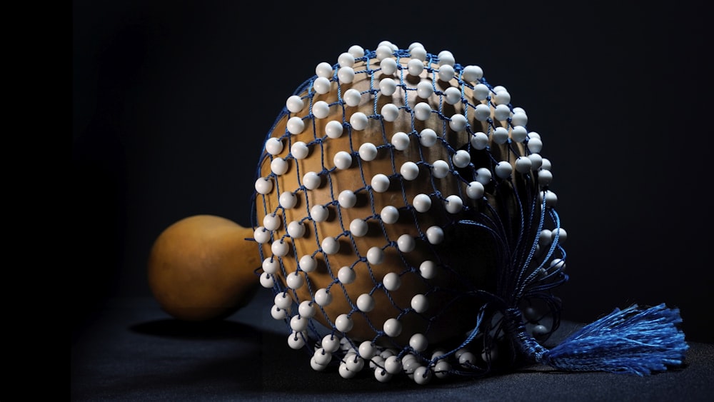 un objet en bois avec des perles blanches et un pompon bleu