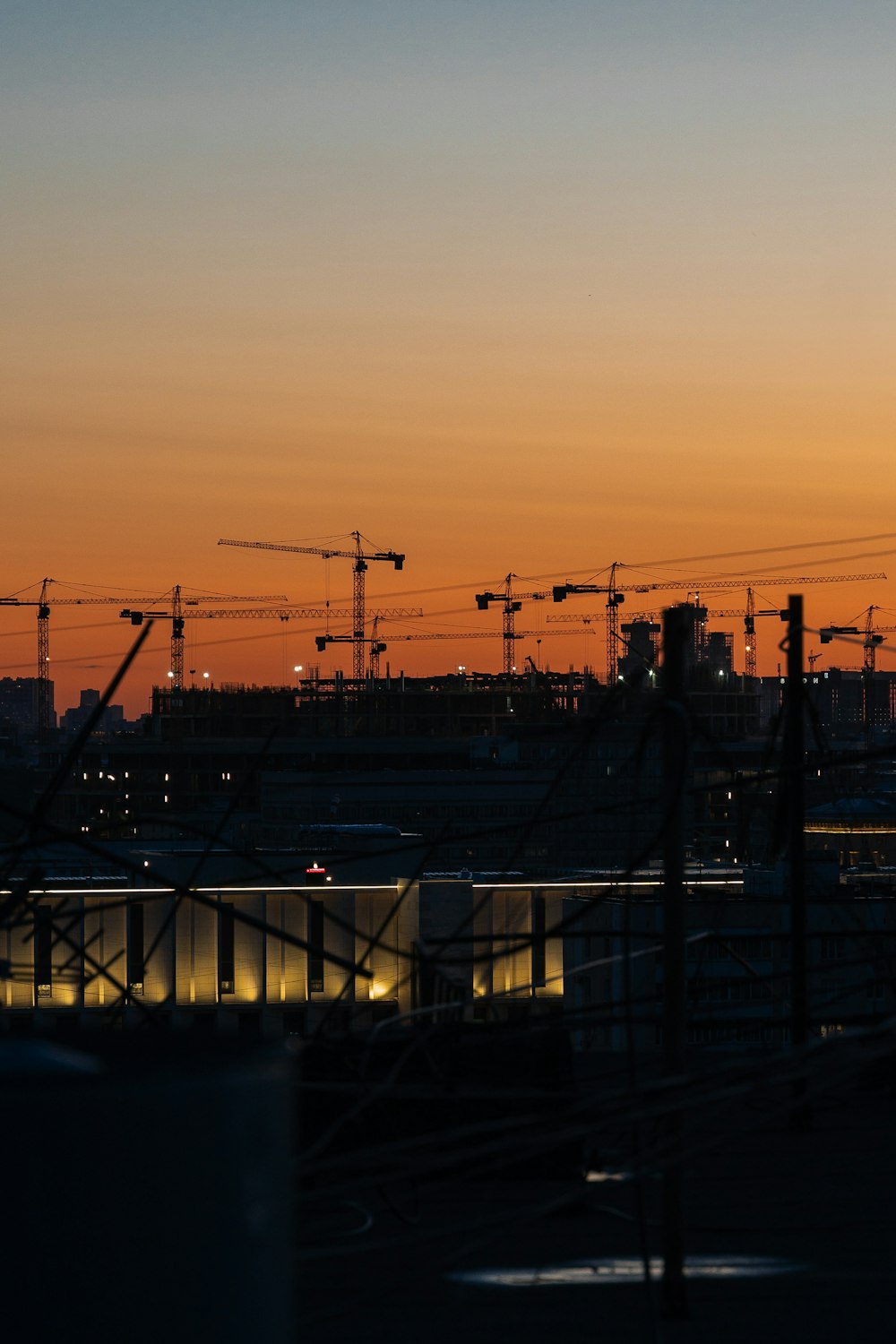 a sunset view of a city with cranes in the background