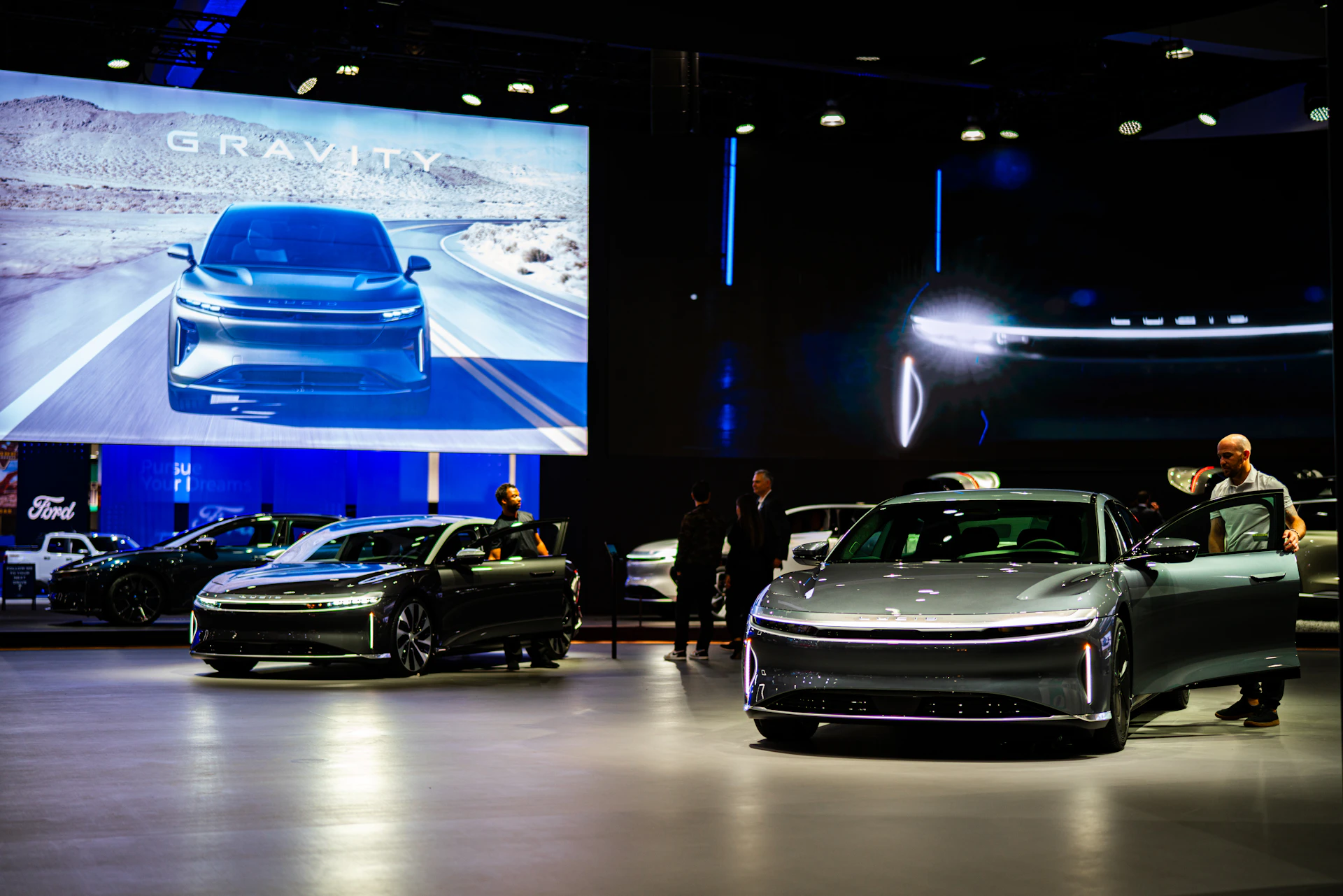 a group of people standing around a bunch of cars