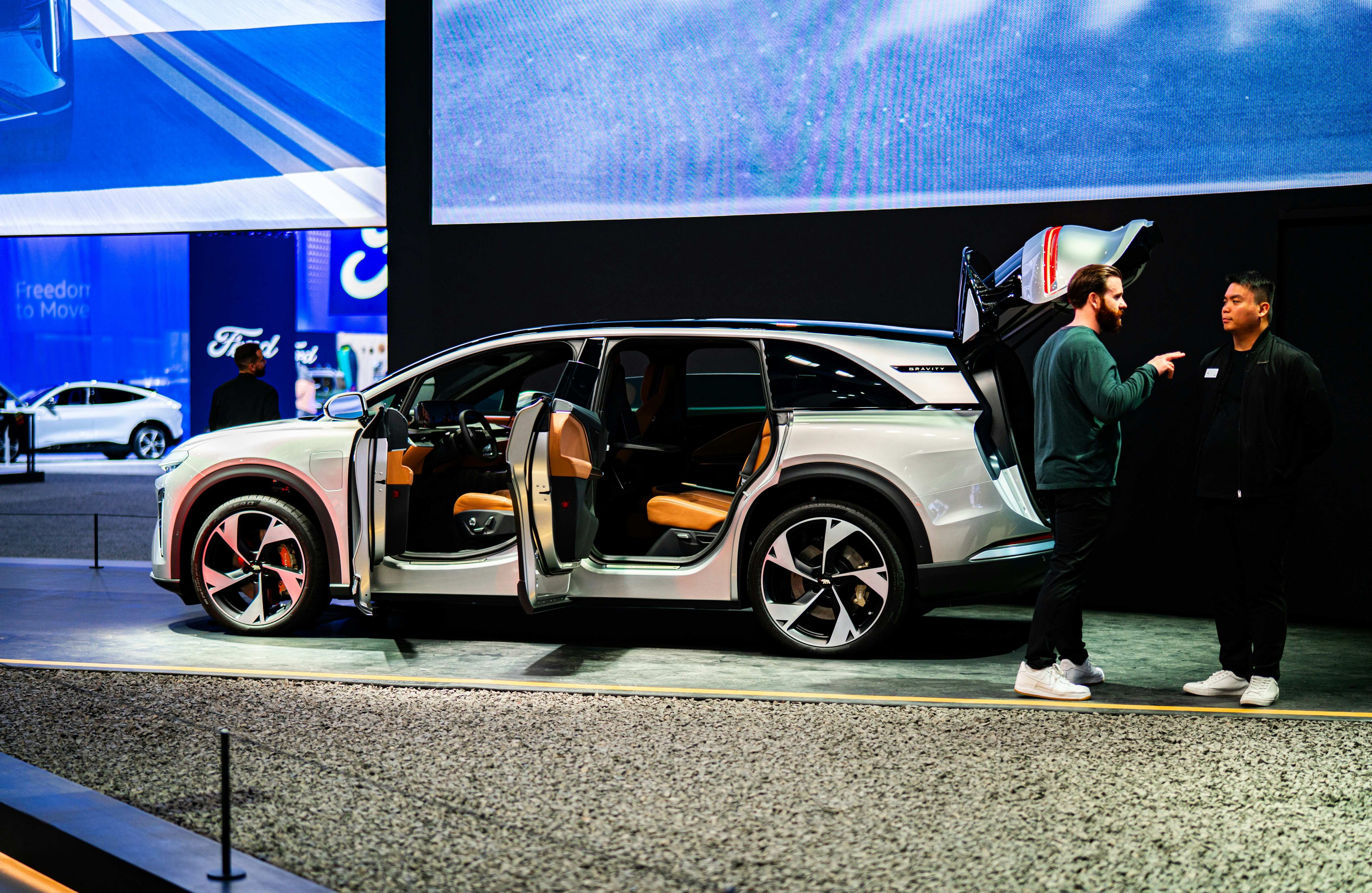 Un couple d’hommes debout à côté d’une voiture blanche